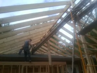Rafters going up over a new addition with a worker on the wall in Wilmore