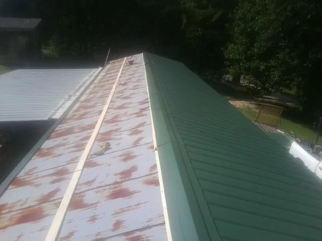Old rusted panels beside newly installed green metal roofing — Wind Damage Roof Repair by Roofing Brothers in Wilmore